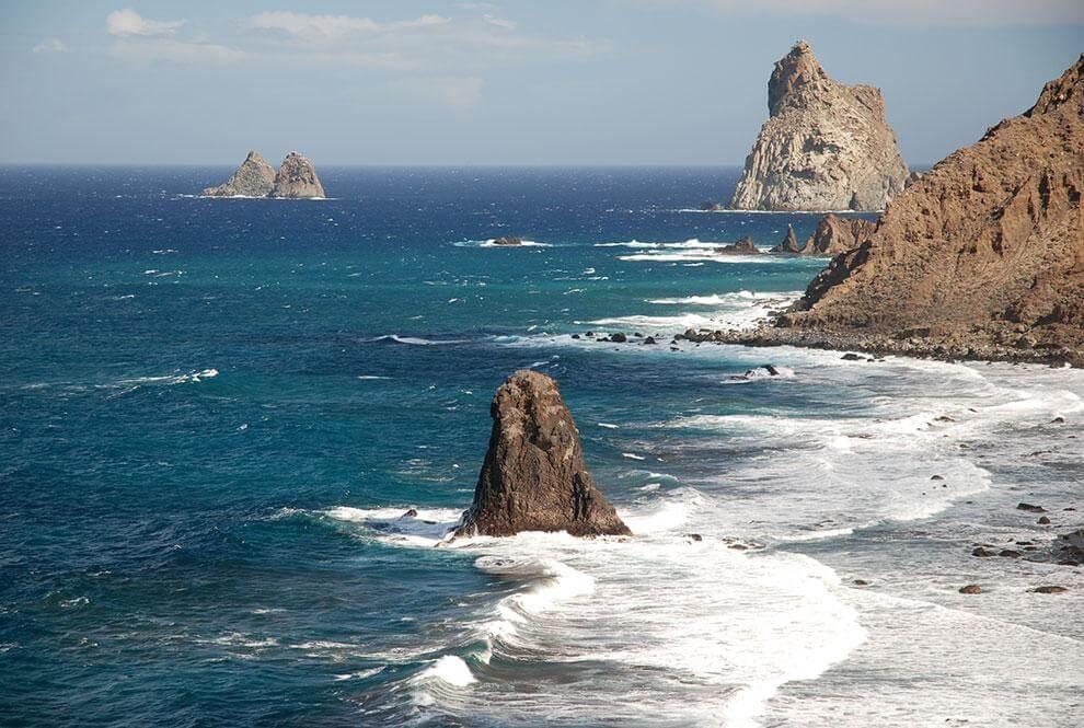 Pilt näitab Tenerife rannikul kaljusid ja ookeani, ideaalne loodusvaade.