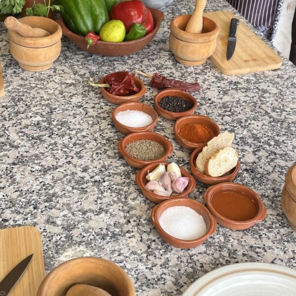 Köögilaual on erinevad vürtsid, küüslauk, tomat, paprika ja maitseained, valmis toiduvalmistami.