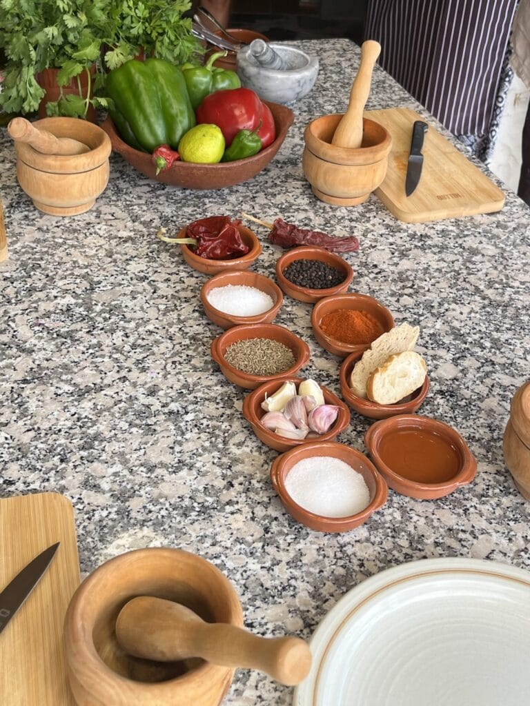 Köögilaual on erinevad vürtsid, küüslauk, tomat, paprika ja maitseained, valmis toiduvalmistami.