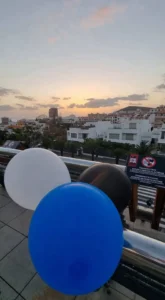 Päikeseloojang Tenerife linnapildis koos siniste ja mustade õhupallidega.