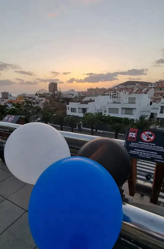 Päikeseloojang Tenerife linnapildis koos siniste ja mustade õhupallidega.