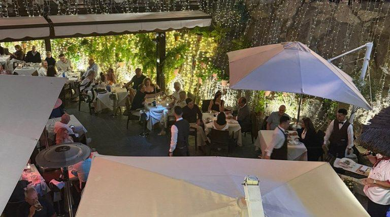 Õhtusöögi restoran Tenerifel, õues, päikesevarju ja rohelise taustaga.